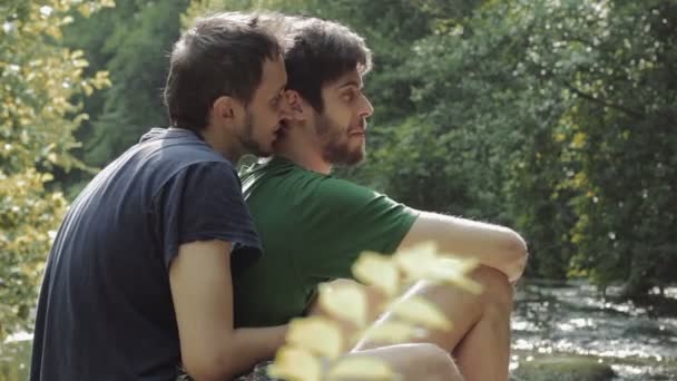 Twee jonge mannen flirten in het park met vijver op achtergrond — Stockvideo