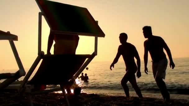 Silhuetten av människor njuter av solnedgången på stranden på en sommardag — Stockvideo