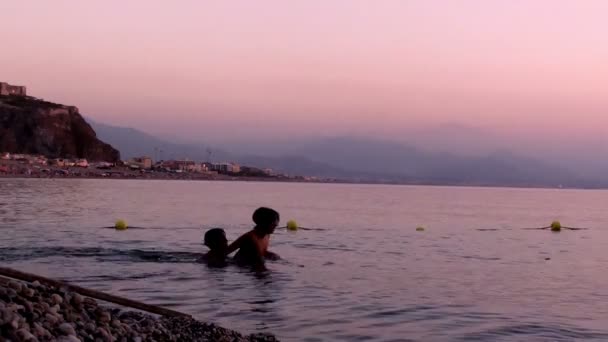 Gyermekek játszanak a vízben, a naplemente — Stock videók