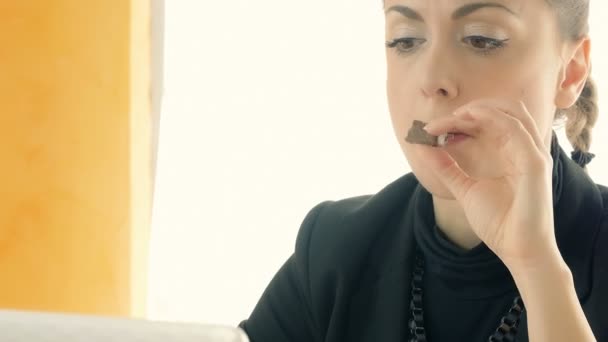 Femme d'affaires manger du chocolat tout en travaillant avec un ordinateur portable — Video