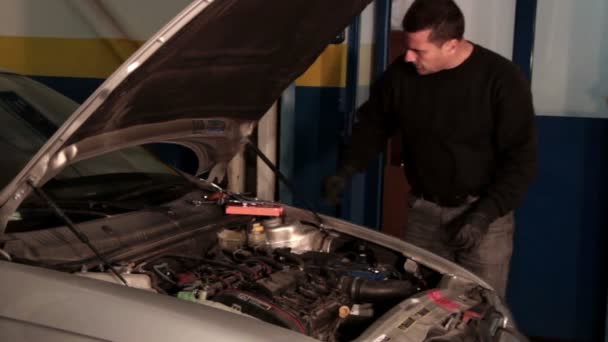 Mecánico de automóviles reparando una parte de un motor de coche — Vídeo de stock