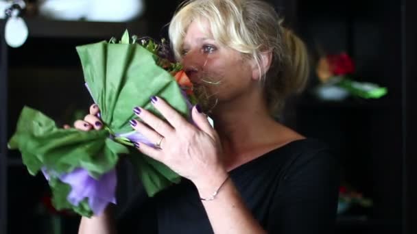 Зріла жінка глибоко нюхає букет квітів — стокове відео