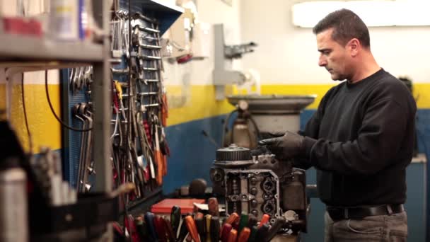 Mecánico de automóviles reparando una parte de un motor de coche — Vídeo de stock