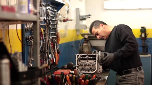 Mecánico de automóviles reparando una parte de un motor de coche — Vídeo de stock