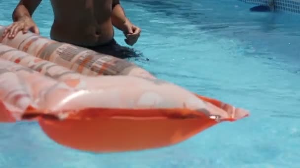 Hombre joven flotando en un colchón en la piscina de agua — Vídeo de stock