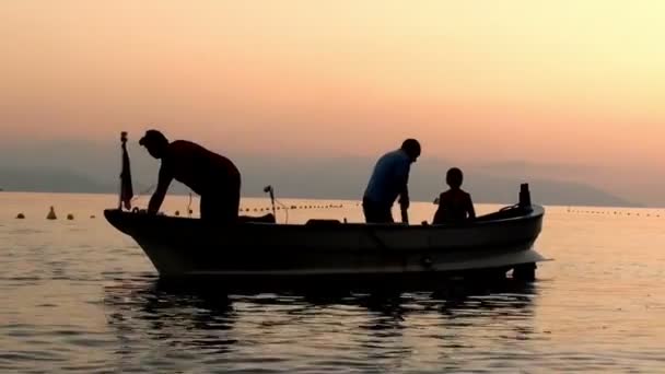 Silhouette dei pescatori sulla barca al tramonto in partenza per la pesca — Video Stock