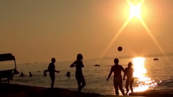 As pessoas jogam vôlei na praia t o pôr do sol — Vídeo de Stock