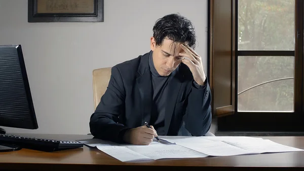 Absorbido hombre de negocios estudia su presentación de negocios, playng con una pluma Imágenes De Stock Sin Royalties Gratis