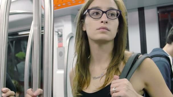 Young woman in metro wagon observing other passengers — ストック動画