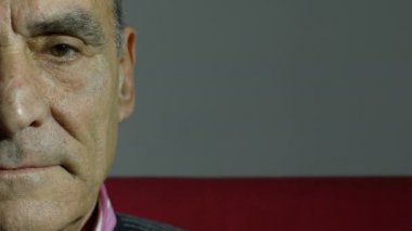 Kırmızı koltuk üzerinde gülümseyen yaşlı adam