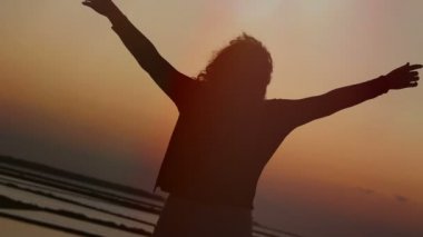 kadın gökyüzü günbatımı contemplates ve kollarını açar: özgürlük, refah