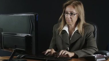 siyah arka plan ile ofisinde bilgisayarda çalışan Sekreter