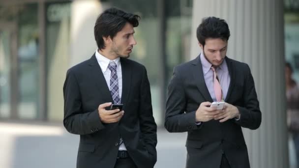 Hombres de negocios caminando y usando teléfonos móviles — Vídeos de Stock