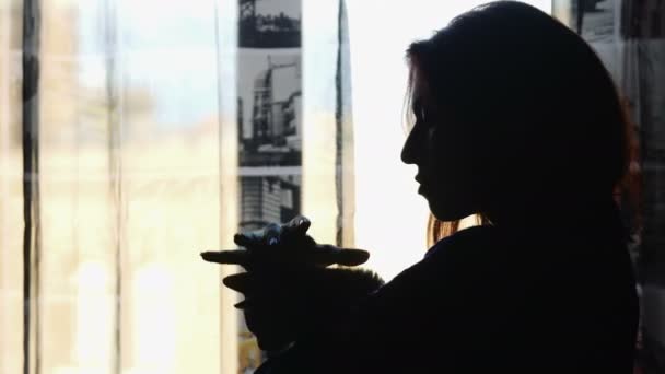 Genç kadın pencerenin önünde küçük bir kedi ile oynarken — Stok video