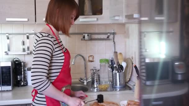 Jonge vrouw is koken in de keuken — Stockvideo