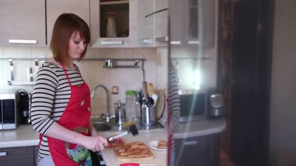 Jonge vrouw is koken in de keuken — Stockvideo