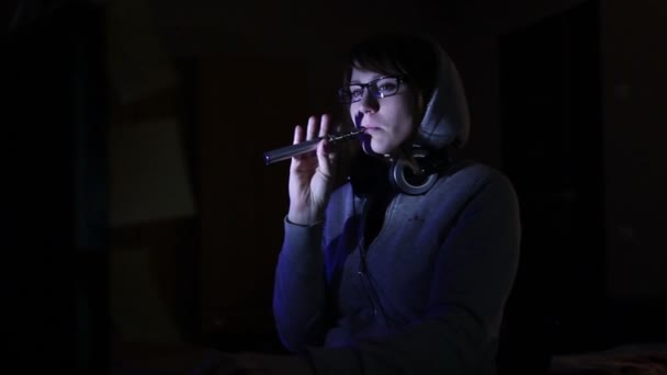 Hacker-Mädchen arbeitet am Computer und raucht elektronische Zigarette — Stockvideo