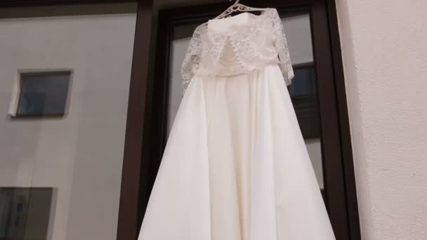 Beautiful wedding dress hanging in a window. — Stock Video