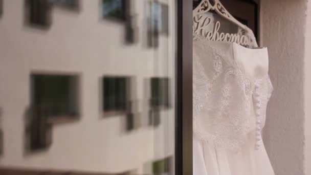 Beautiful wedding dress hanging in a window. — Stock Video