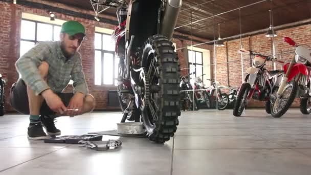 Mężczyzna sportowiec naprawy jego motocykl enduro — Wideo stockowe