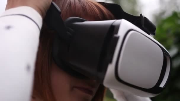 Mujer pelirroja joven usando casco VR para teléfonos inteligentes. Realidad aumentada — Vídeos de Stock