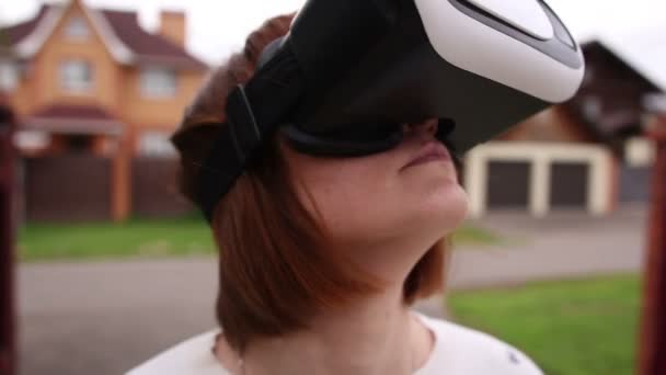 Mujer pelirroja joven usando casco VR para teléfonos inteligentes. Realidad aumentada — Vídeo de stock