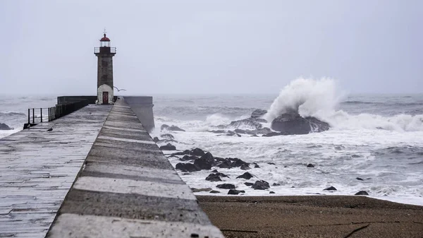 Storm waves next to a lighthouse on the ocean