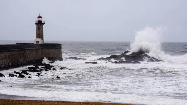 Storm waves next to a lighthouse on the ocean
