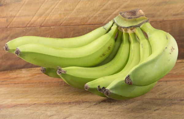 Bunch of green bananas on a wooden background — Stock Photo, Image