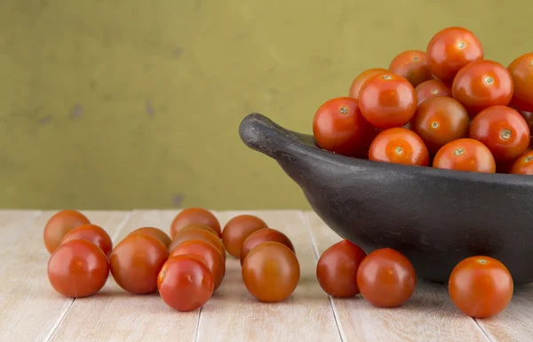 Set of cherry tomatoes in bowl on wooden background.
