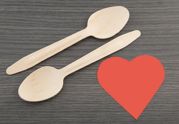 Dos cucharas de madera sobre fondo y corazón de madera —  Fotos de Stock