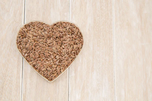 Alimento sano de la dieta sanitaria. Semillas de lino crudo corazón de linaza en forma de tablero de madera de fondo . — Foto de Stock