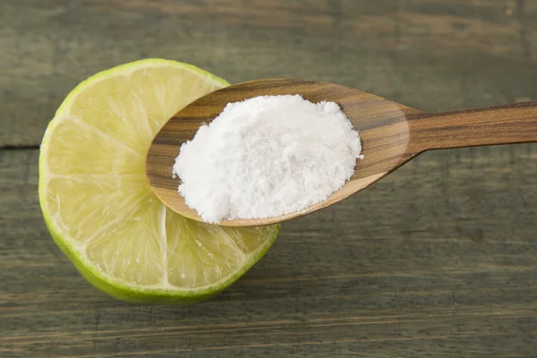 Bicarbonato de sodio en una cuchara de madera y limón — Foto de Stock