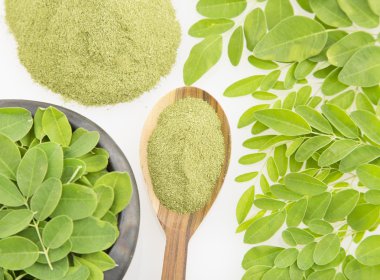 Moringa yaprakları ve beyaz arka plan üzerinde tozu