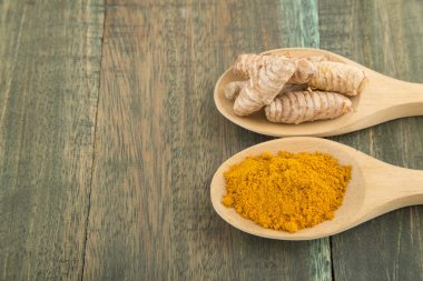 kaşık ve kökleri ahşap plaka üzerinde zerdeçal tozu