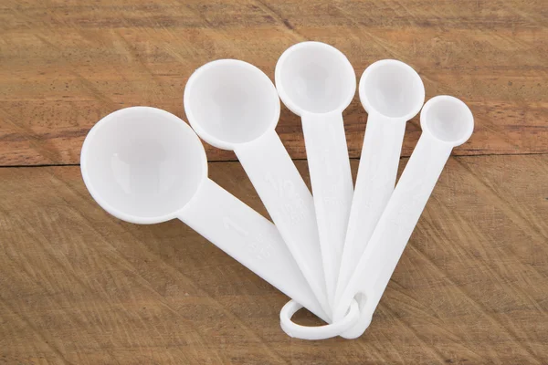Plastic measuring spoons on a wooden background — Stock Photo, Image
