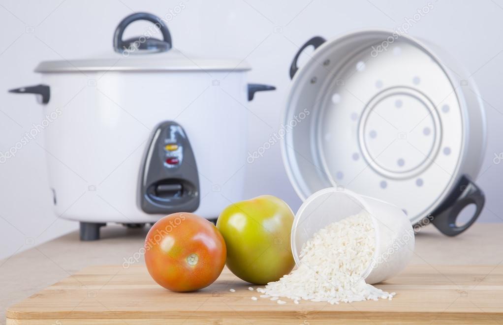 White rice cooker with accessory to cook steamed vegetables Stock Photo