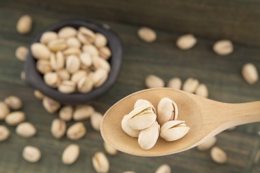 Ahşap arka plan üzerinde kase ve kaşık antep fıstığı
