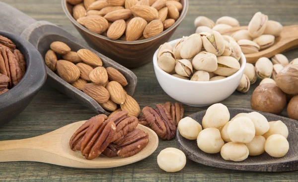 Grupo de nueces sobre mesa de madera. Almendras, pistachos, macadamia y nuez de pacana — Foto de Stock