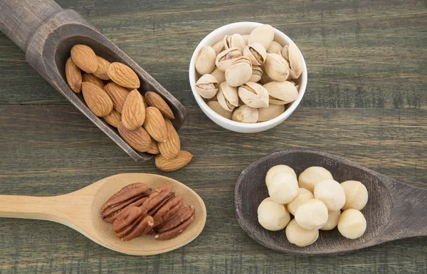 Grupo de nueces sobre mesa de madera. Almendras, pistachos, macadamia y nuez de pacana — Foto de Stock