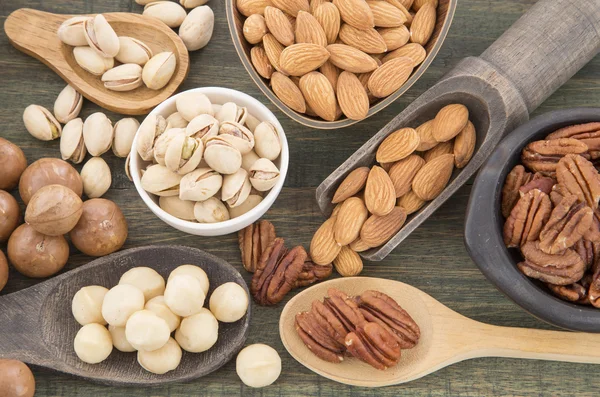 Grupo de nueces sobre mesa de madera. Almendras, pistachos, macadamia y nuez de pacana — Foto de Stock