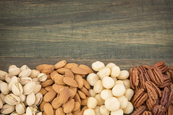 Grupo de nueces sobre mesa de madera. Almendras, pistachos, macadamia y nuez de pacana — Foto de Stock