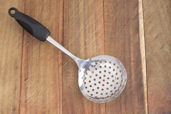 Silver spoon colander, isolated on wooden background — Stock Photo, Image