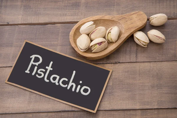 Pistachios on the table and wooden spoon