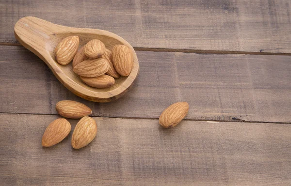 Almendras sobre la mesa y cuchara de madera — Foto de Stock