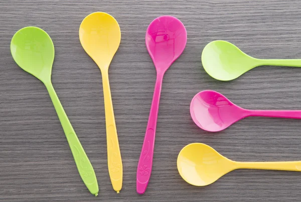 Colorful plastic spoons on wooden background — Stock Photo, Image