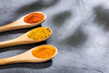 Tahta kaşıklarda köri, zerdeçal ve kırmızı biber baharatları.