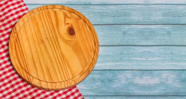 Kırsal arka planda kırmızı kareli peçeteli yuvarlak kesim tahtası