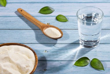 Kaşıkta toz kolajen protein var. Bir bardak su.