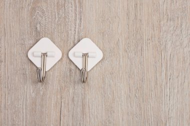 İki plastik yapıştırıcı duvarda asılı elbiseler için metal kancalarla tutturulmuş.